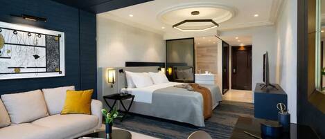 A modern hotel room with a bed, a sofa, a coffee table, and a desk.