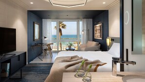 Una habitación de hotel moderna con una cama grande, un escritorio y vistas al océano.