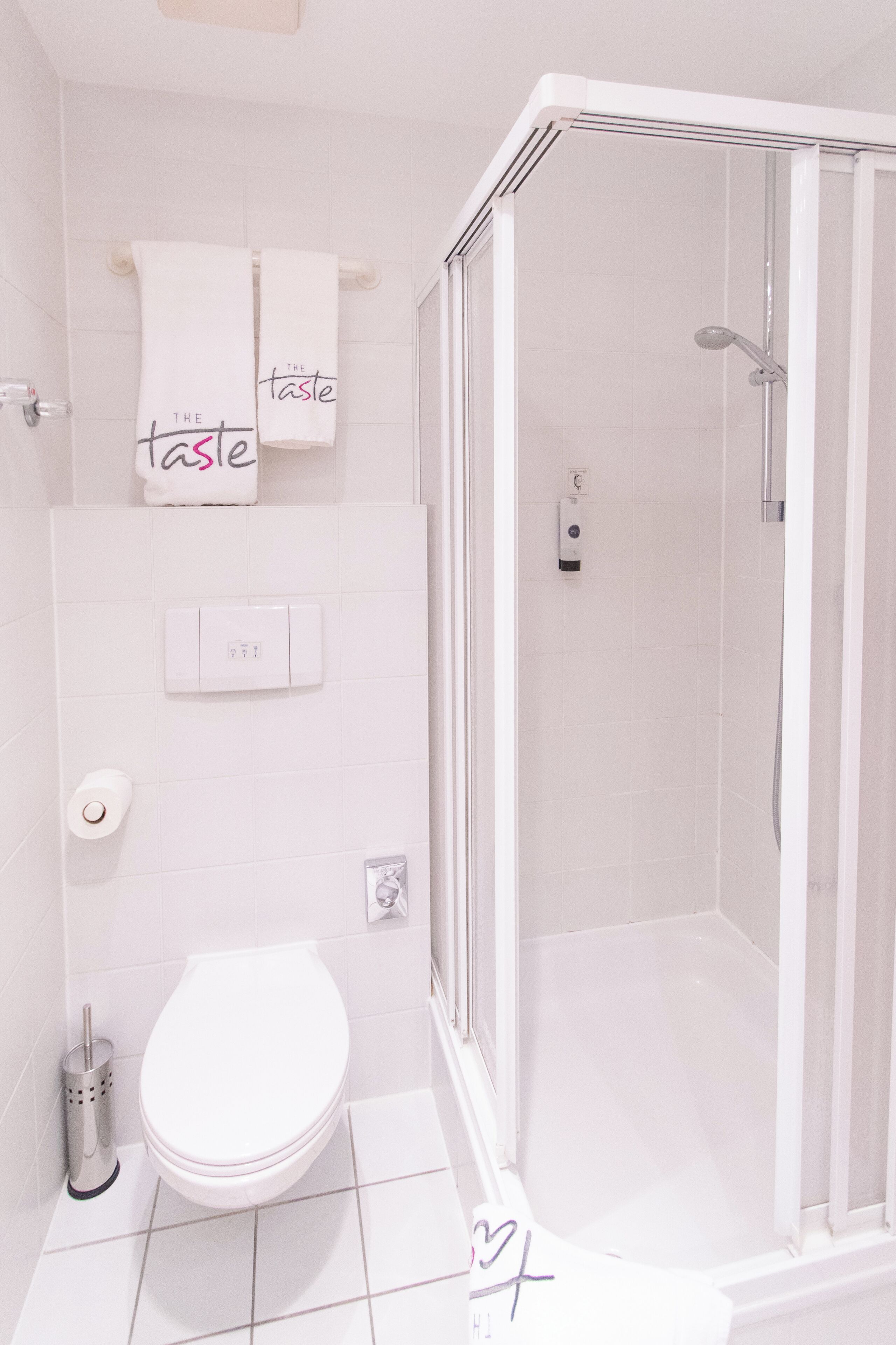 A modern bathroom with a toilet, a shower, and a towel rack with towels.