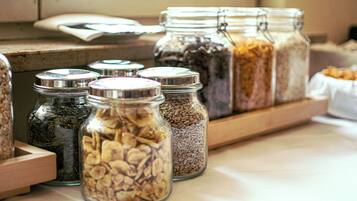 Glass jars with metal lids containing various grains and seeds on a wooden shelf.