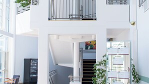 Un atrio de varios niveles con una escalera, un mostrador de recepción y una planta en maceta.