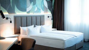 Una habitación de hotel moderna con una cama grande, un escritorio y una silla.