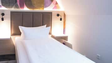 A neatly made bed in a hotel room with a modern headboard, a large abstract painting on the wall, and a blue carpet.