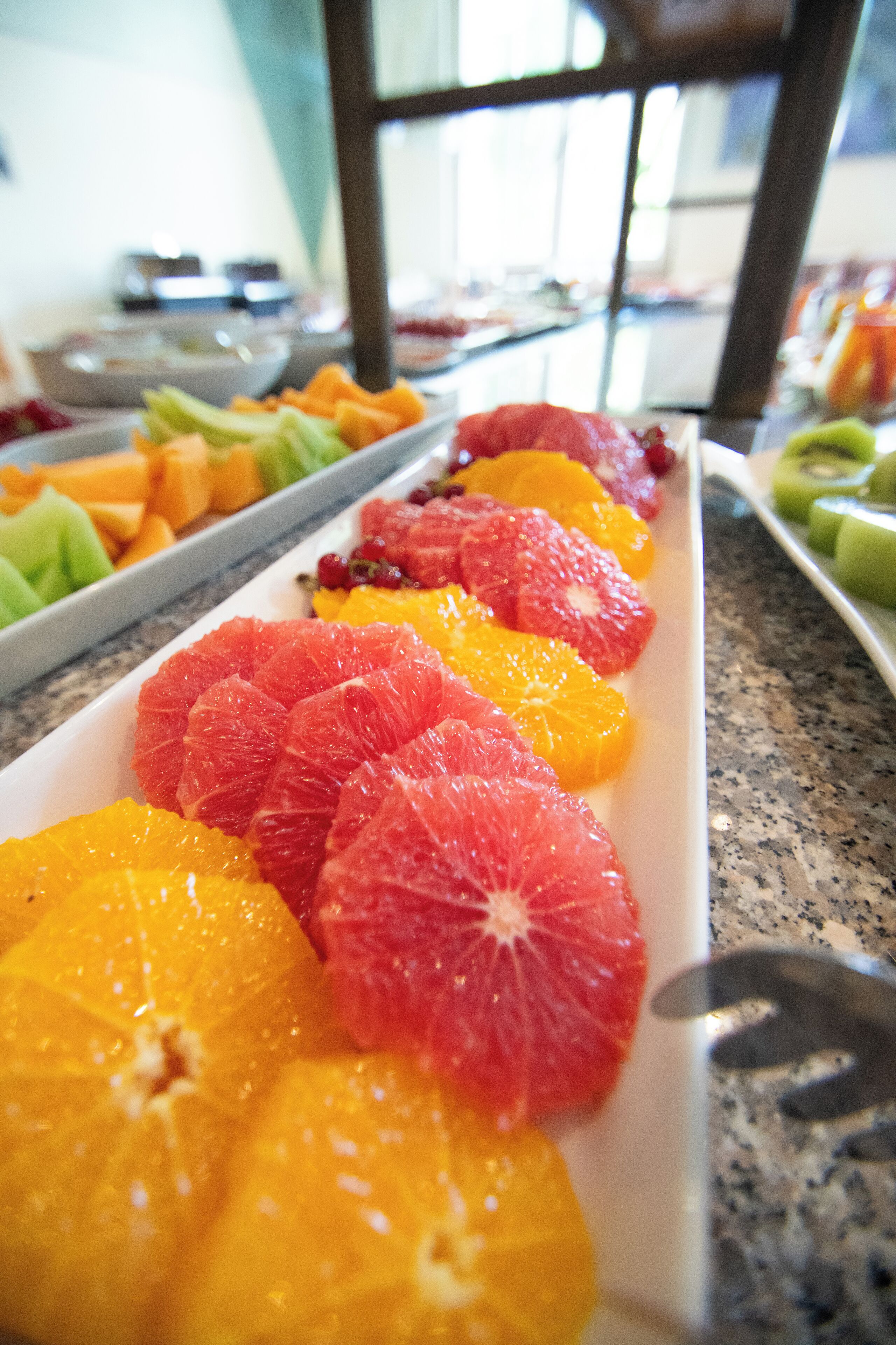 Una mesa de buffet con diversas frutas, incluyendo naranjas y pomelos.