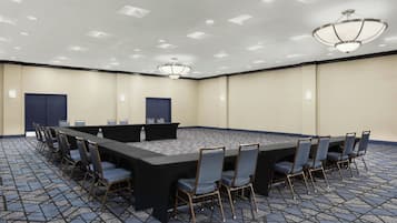 A conference room with a long table, chairs, and a carpeted floor.