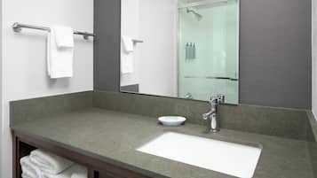 A bathroom with a large mirror, a sink, and a glass shower enclosure.
