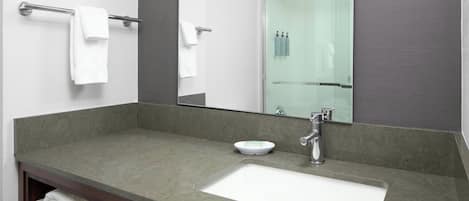 Un baño con un espejo grande, un lavabo y una cabina de ducha de vidrio.