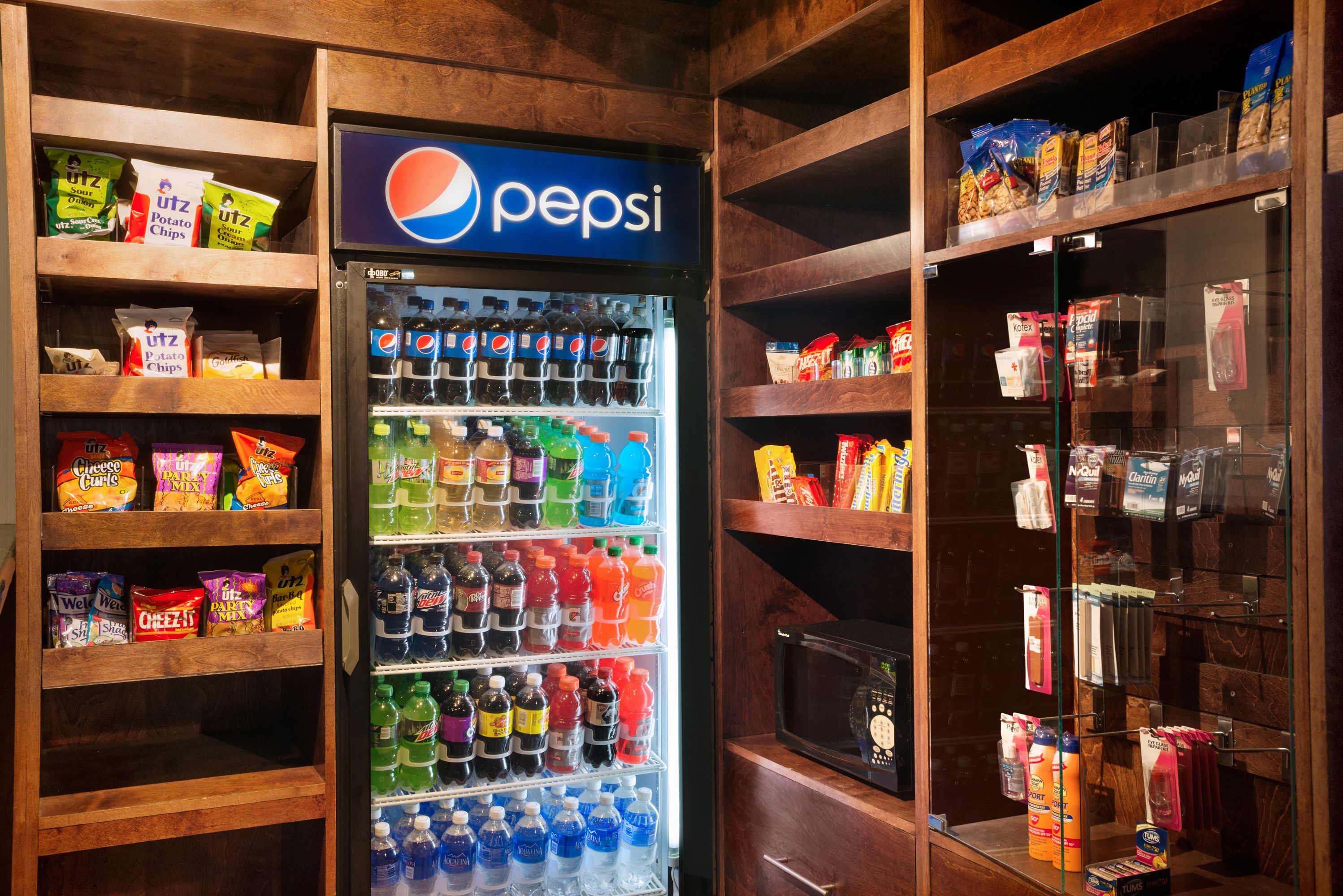A vending machine stocked with snacks and drinks, including Pepsi, and surrounded by shelves with various packaged goods.