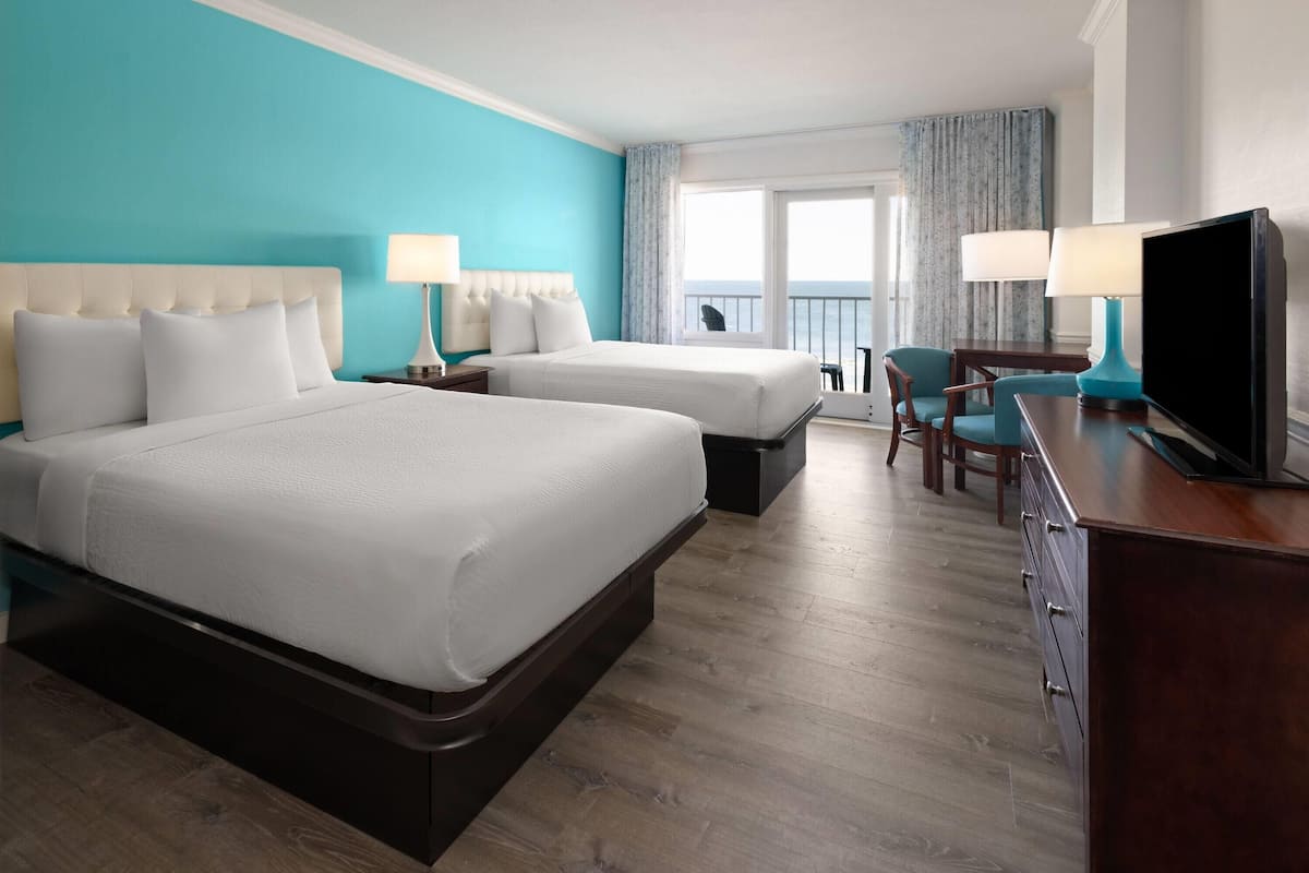 Une chambre d’hôtel avec deux lits, une télévision, un bureau et une chaise.