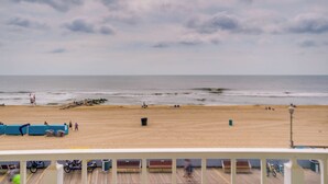 A beach with a wooden deck, benches, and bicycles.