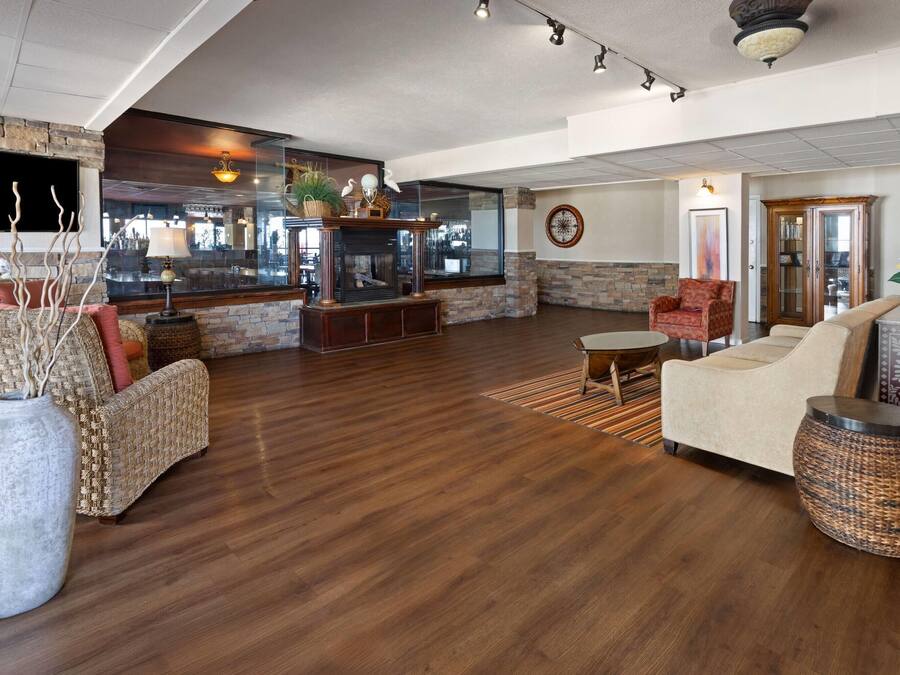 Ampla sala de estar com lareira, assentos confortáveis e uma grande janela com vista para o interior.