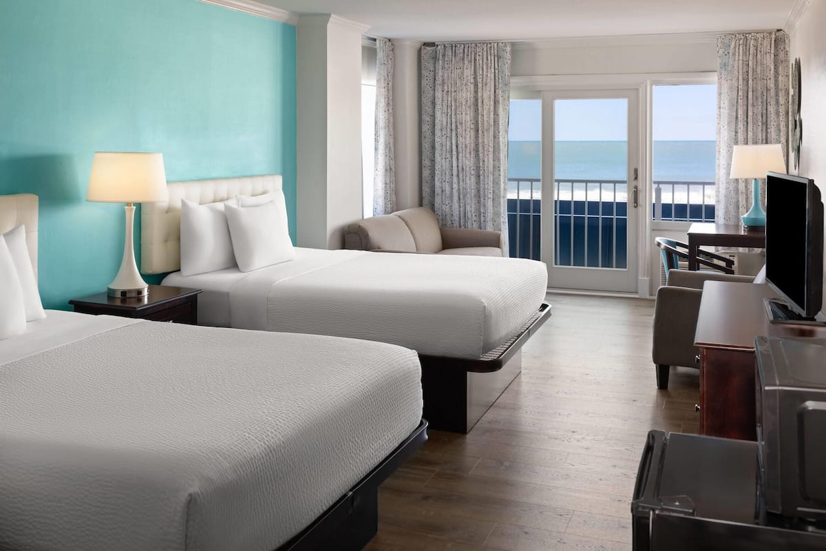 Une chambre d’hôtel avec deux lits, un bureau, une chaise et un téléviseur.