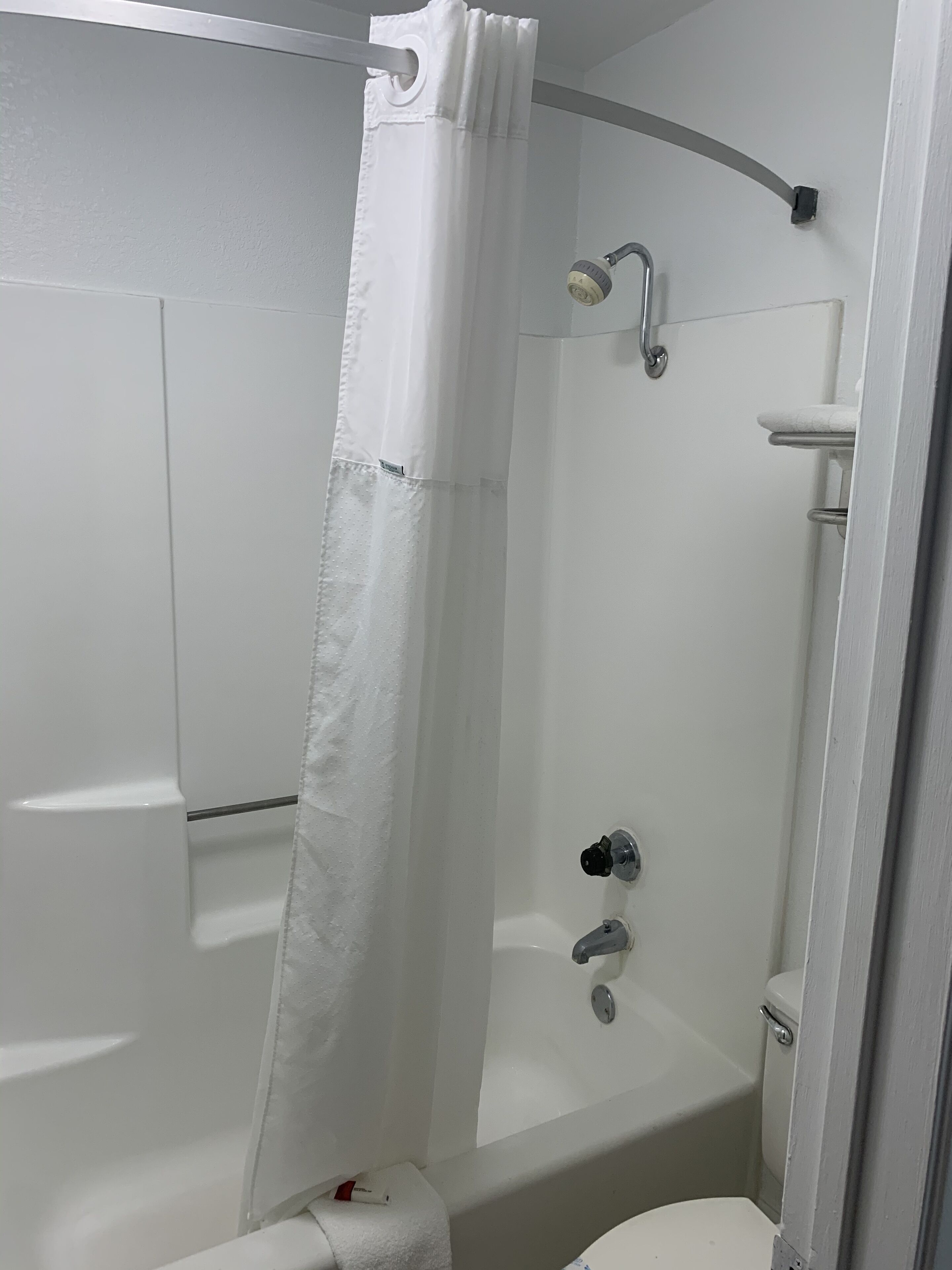 A bathroom with a shower, toilet, and a towel rack.