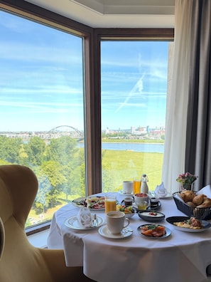 A dining table with breakfast items and a view of a bridge and cityscape. - Crowne Plaza Düsseldorf-Neuss by IHG (Neuss)