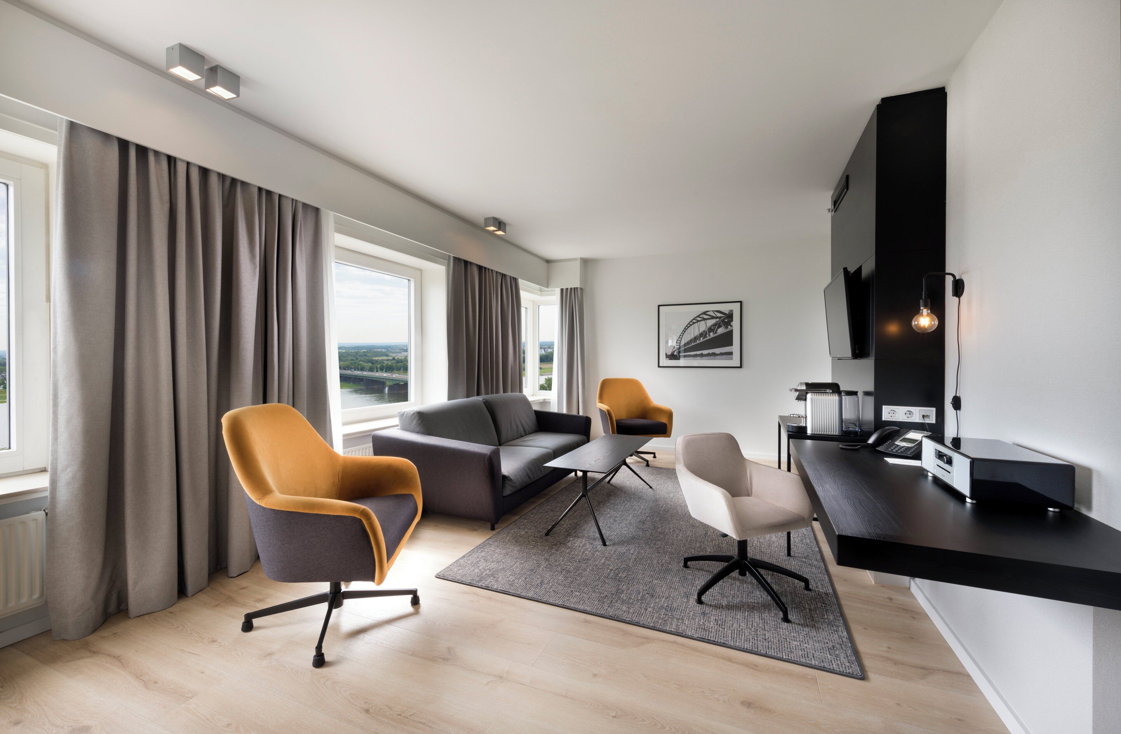 A modern living room with a sofa, two armchairs, a coffee table, and a TV.