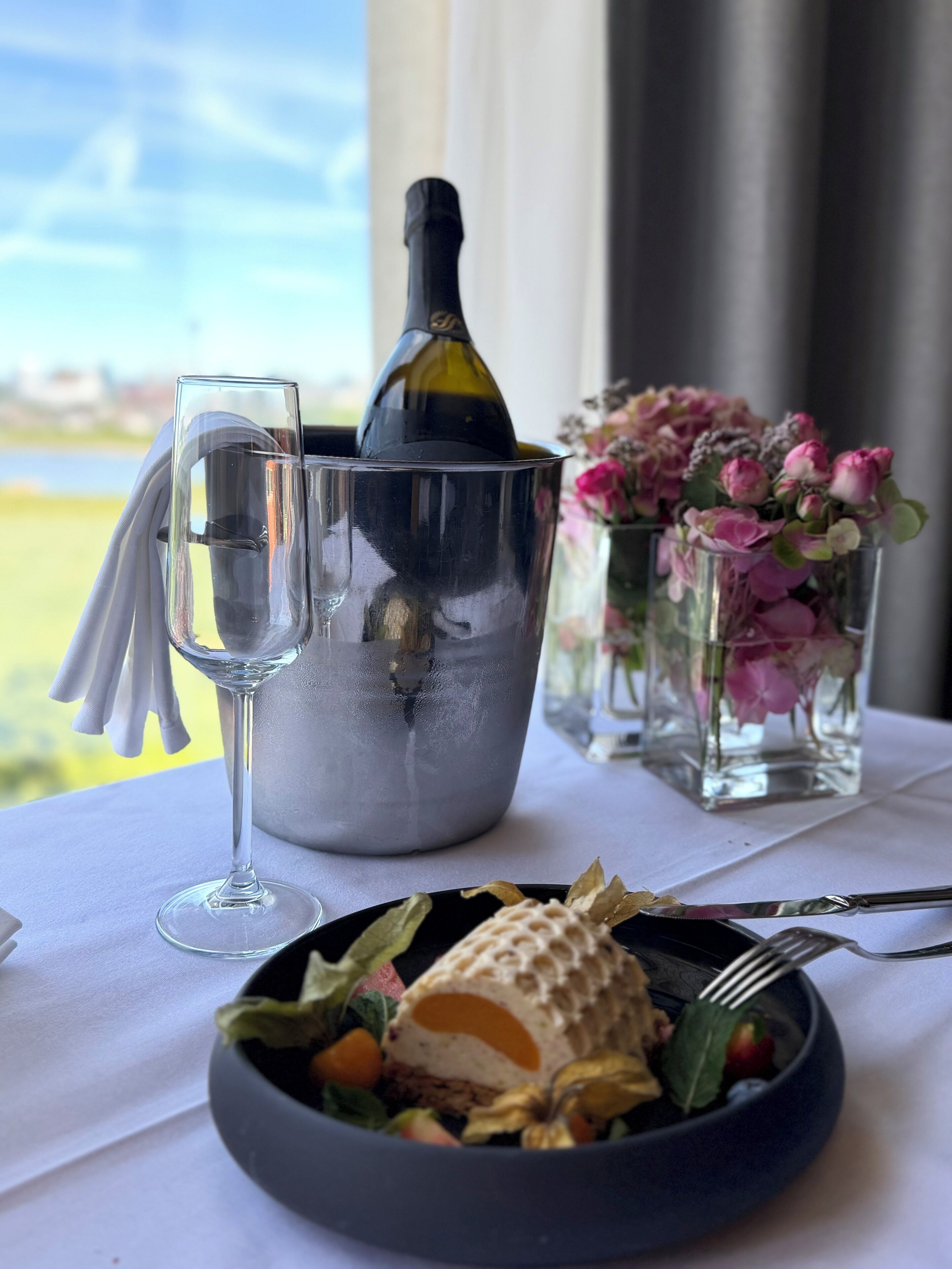 Ein Esstisch mit einer Champagnerflasche, einem Glas und einer Salatschüssel.