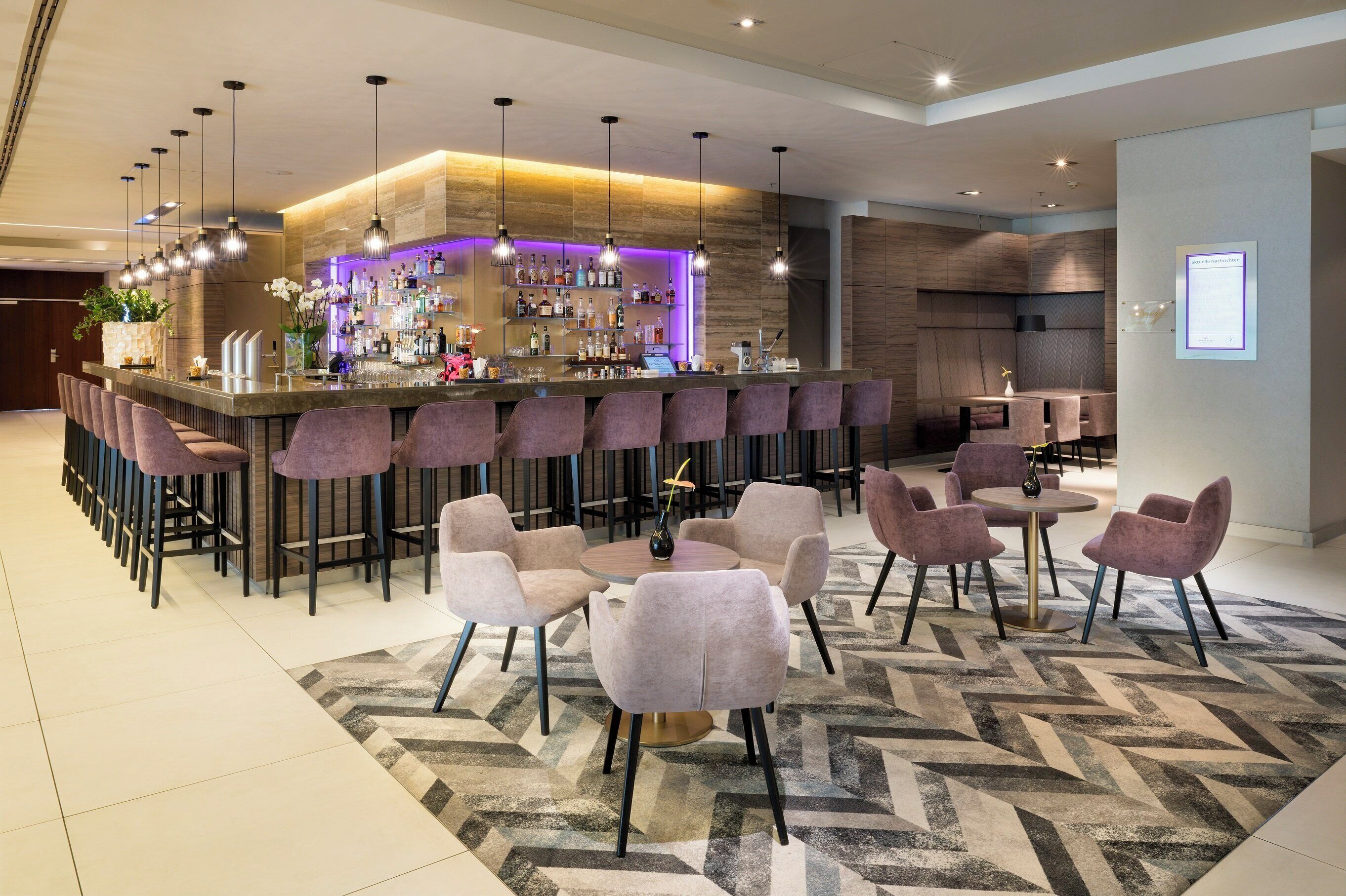 A modern bar area with a bar counter, multiple seating options, and a patterned floor.