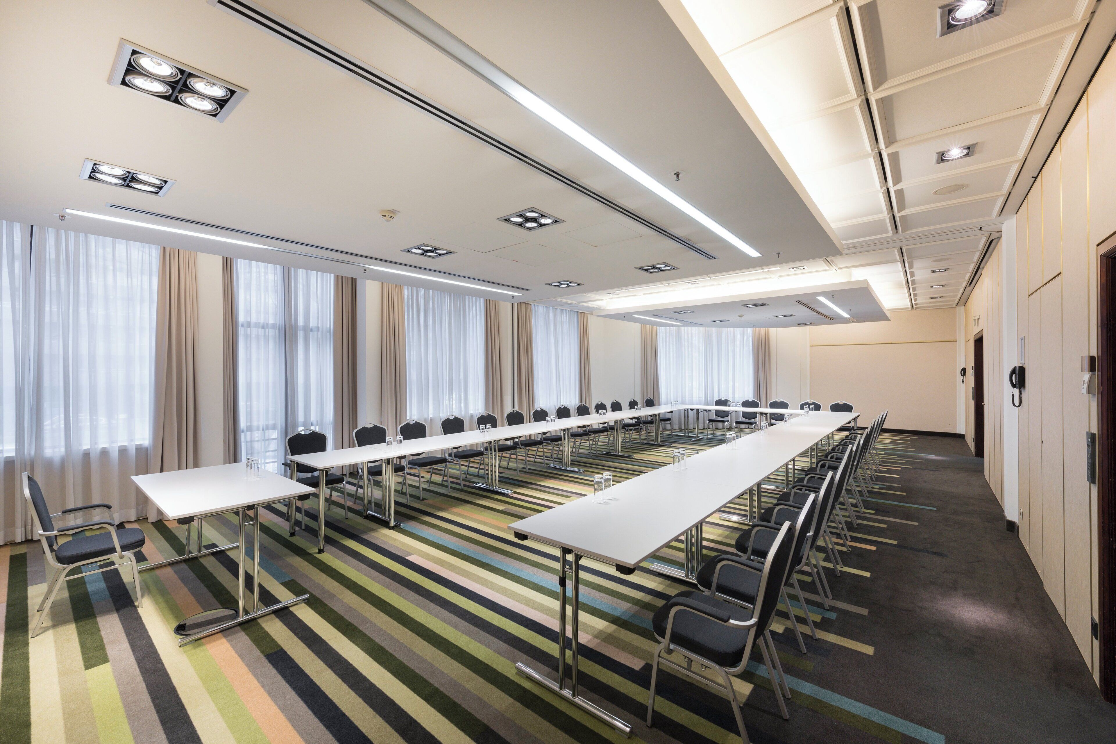 Una sala de conferències amb una taula llarga, cadires i una catifa de ratlles.