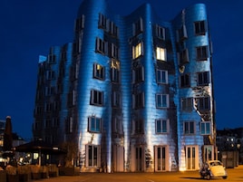 Un edificio moderno con una arquitectura curva distintiva, con varias ventanas y una entrada bien iluminada.