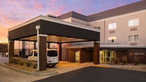 Ein modernes Hotel mit überdachtem Parkbereich, einem Lieferwagen und einem Schild mit der Aufschrift 'La Quinta'.