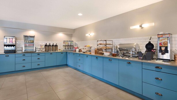 A kitchen with blue cabinets, a coffee machine, and a refrigerator. - Country Inn & Suites by Radisson, Chippewa Falls, WI (Chippewa Falls)