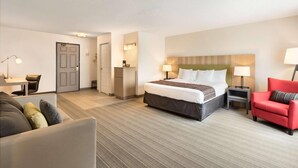 Ein Hotelzimmer mit Bett, Schreibtisch, Stuhl, einem roten Sofa und einem Kleiderschrank.
