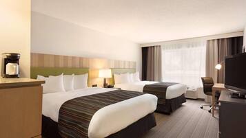 Quarto de hotel com duas camas, uma escrivaninha, televisão e máquina de café.