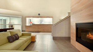 Ein modernes Wohnzimmer mit einer Couch, einem Kamin und einer Küchenzeile im Hintergrund.