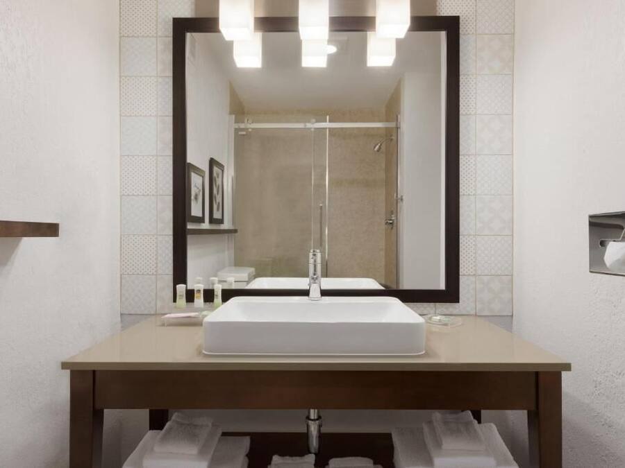 Een badkamer met een grote spiegel, een wastafel en een douche.