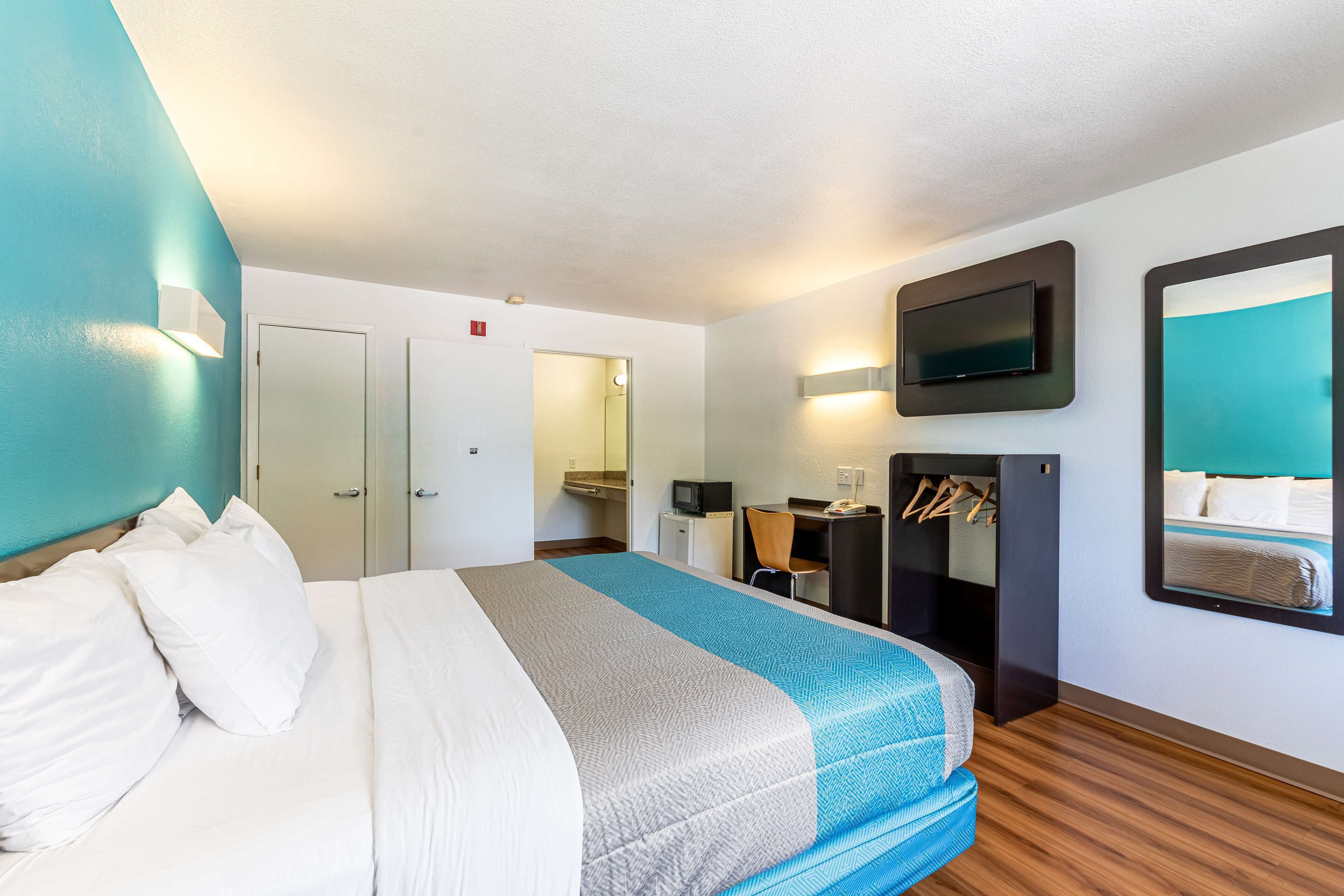 A hotel room with a bed, a desk, a television, and a mirror.