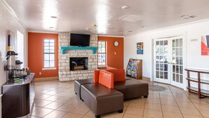 A lobby with a stone fireplace, seating area, and a television.
