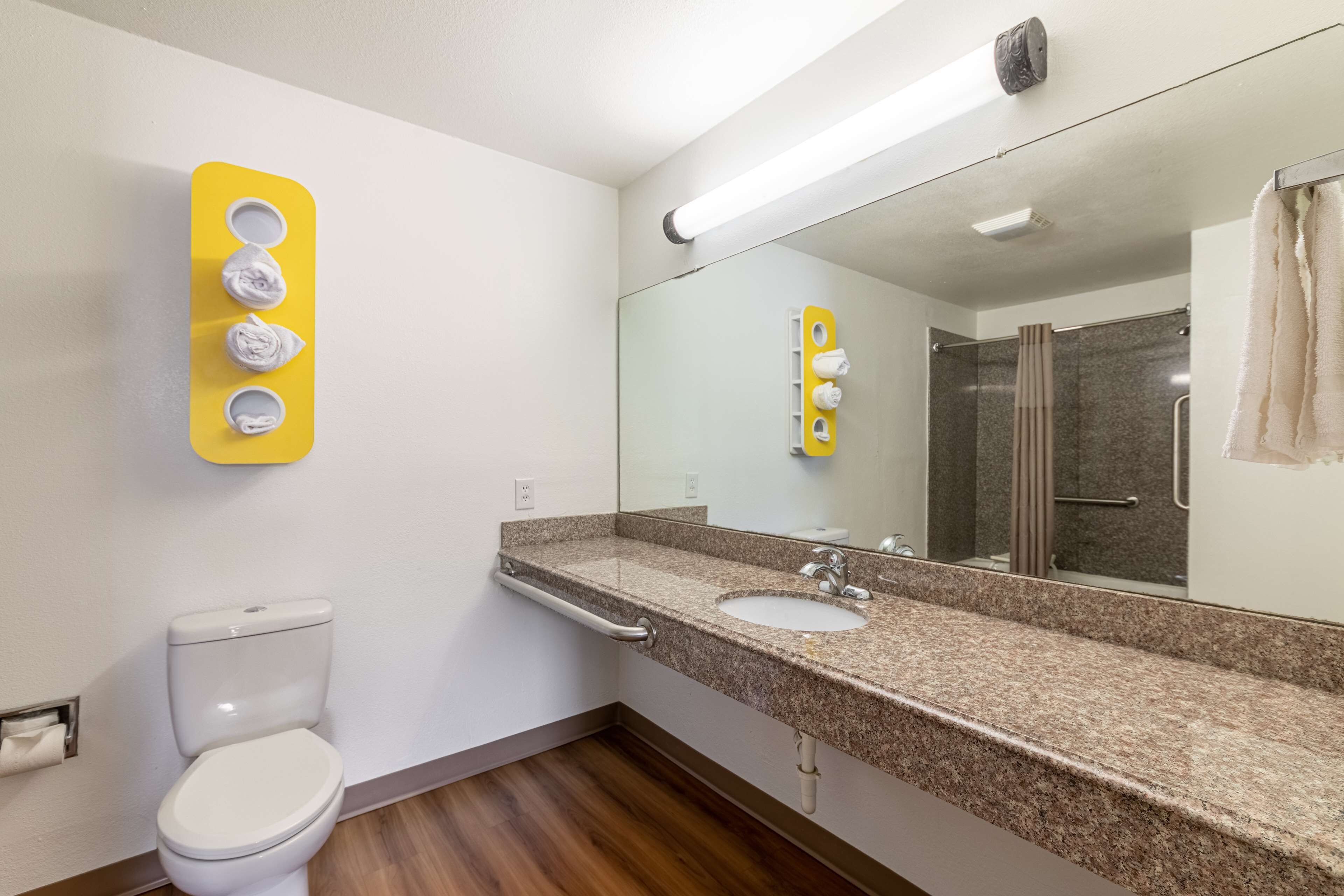 Un baño con inodoro, lavabo, espejo y toallero.