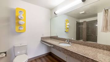 Un baño con inodoro, lavabo, espejo y toallero.