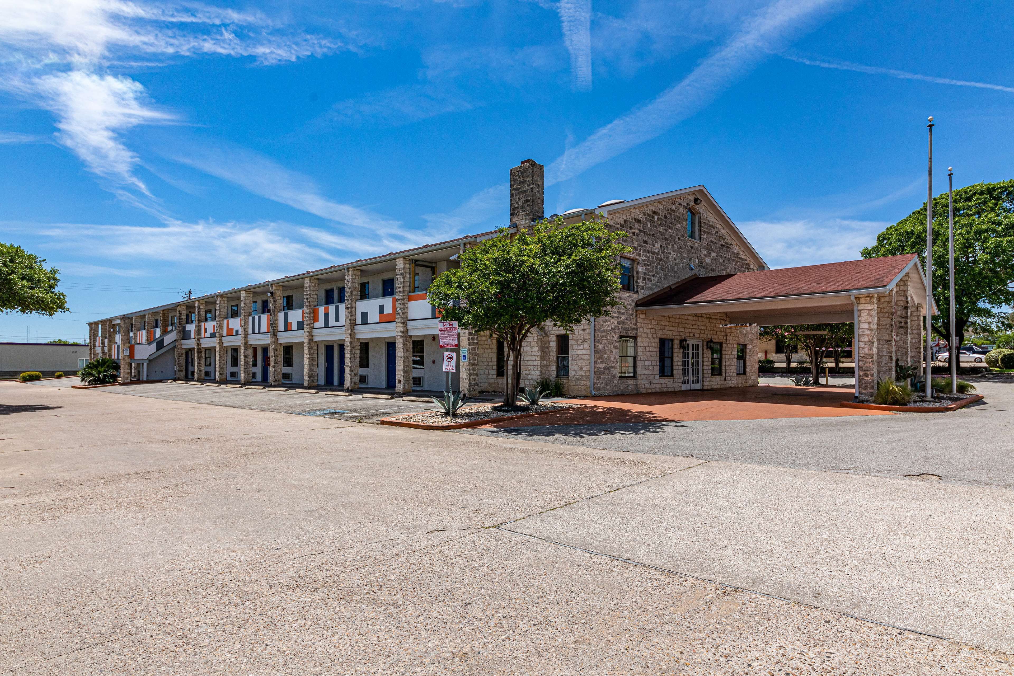 Un motel à deux étages, avec un toit rouge et une façade en pierre.