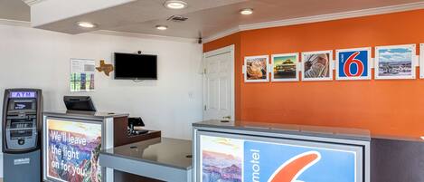 Una recepción de motel con un gran letrero que dice "motel 6" y una pantalla digital mostrando una imagen panorámica.