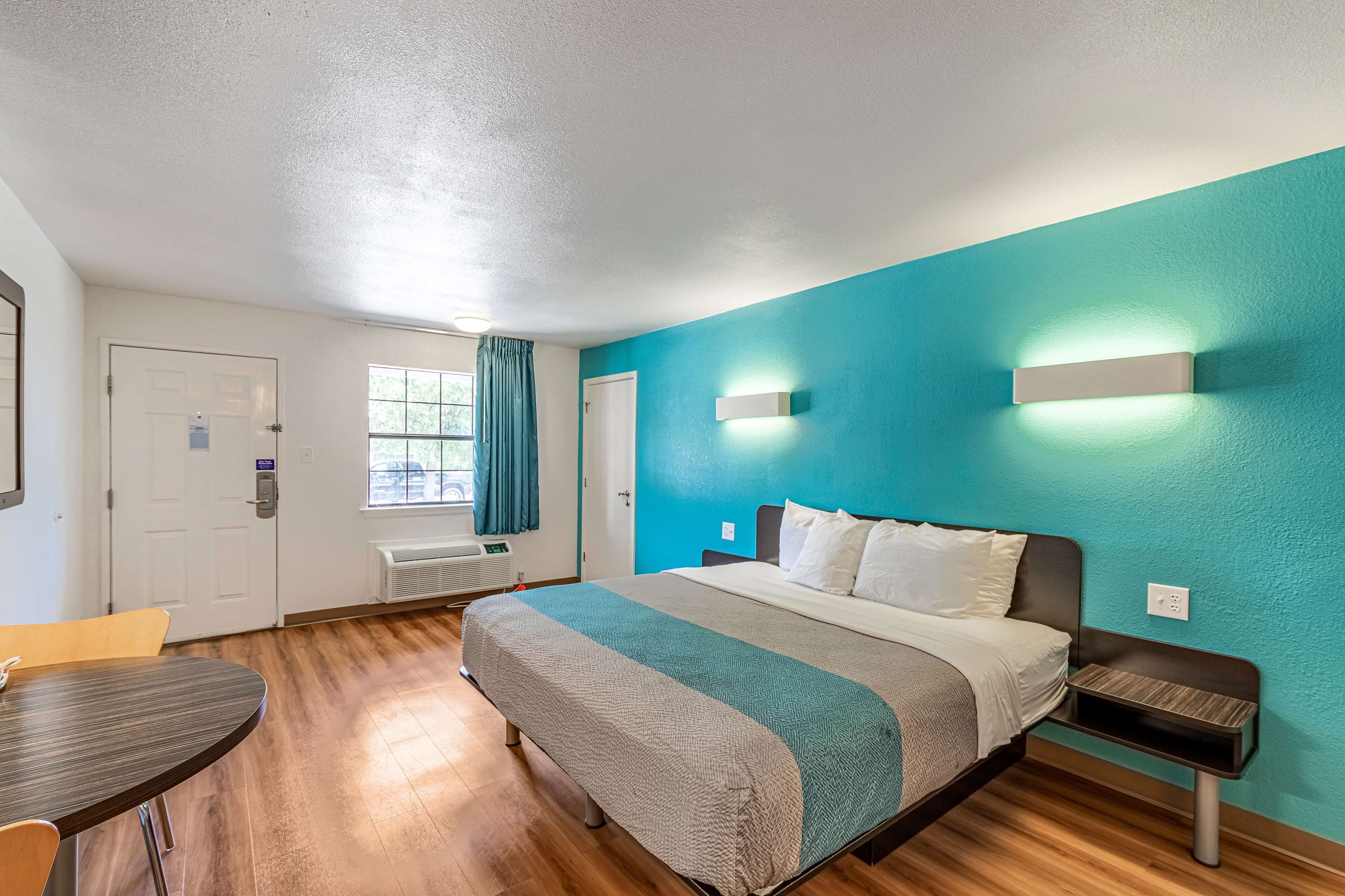 A hotel room with a bed, a desk, and a window with curtains.