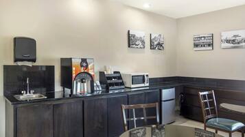 Eine moderne Küche mit schwarzem Arbeitsplatz, Edelstahlgeräten, einer Kaffeemaschine und einer Sitzecke mit Tisch und Stühlen.