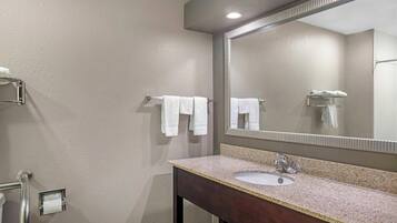 Ein Badezimmer mit Waschbecken, Spiegel, Handtuchhalter und Toilettenpapierhalter.