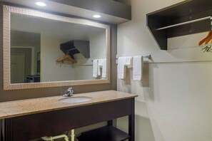 Une salle de bain avec un lavabo, un miroir, un porte-serviettes et une serviette accrochée au mur.