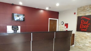 A reception desk with a flat-screen TV, a security camera, and a Red Roof Inn sign.
