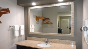 Une salle de bain équipée d’un lavabo, d’un miroir, d’un porte-serviettes et d’un sèche-cheveux.