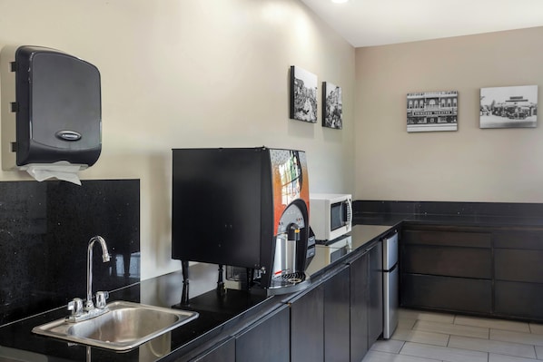 A modern kitchen with a stainless steel sink, a microwave, a coffee machine, and a paper towel dispenser. - Red Roof Inn Columbia, TN (Columbia)