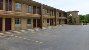 A multi-story motel with a central courtyard, featuring a parking lot with marked spaces.