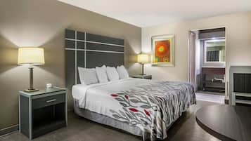 Ein Hotelzimmer mit einem Bett, zwei Nachttischlampen, einem Gemälde, einem Spiegel und einem kleinen Tisch.