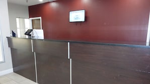 A reception desk with a digital screen displaying 'TRUE RED' Bathroom Amenities' in a hotel lobby.