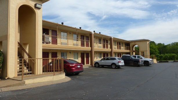 A motel with multiple floors, a parking lot, and a clear sky.