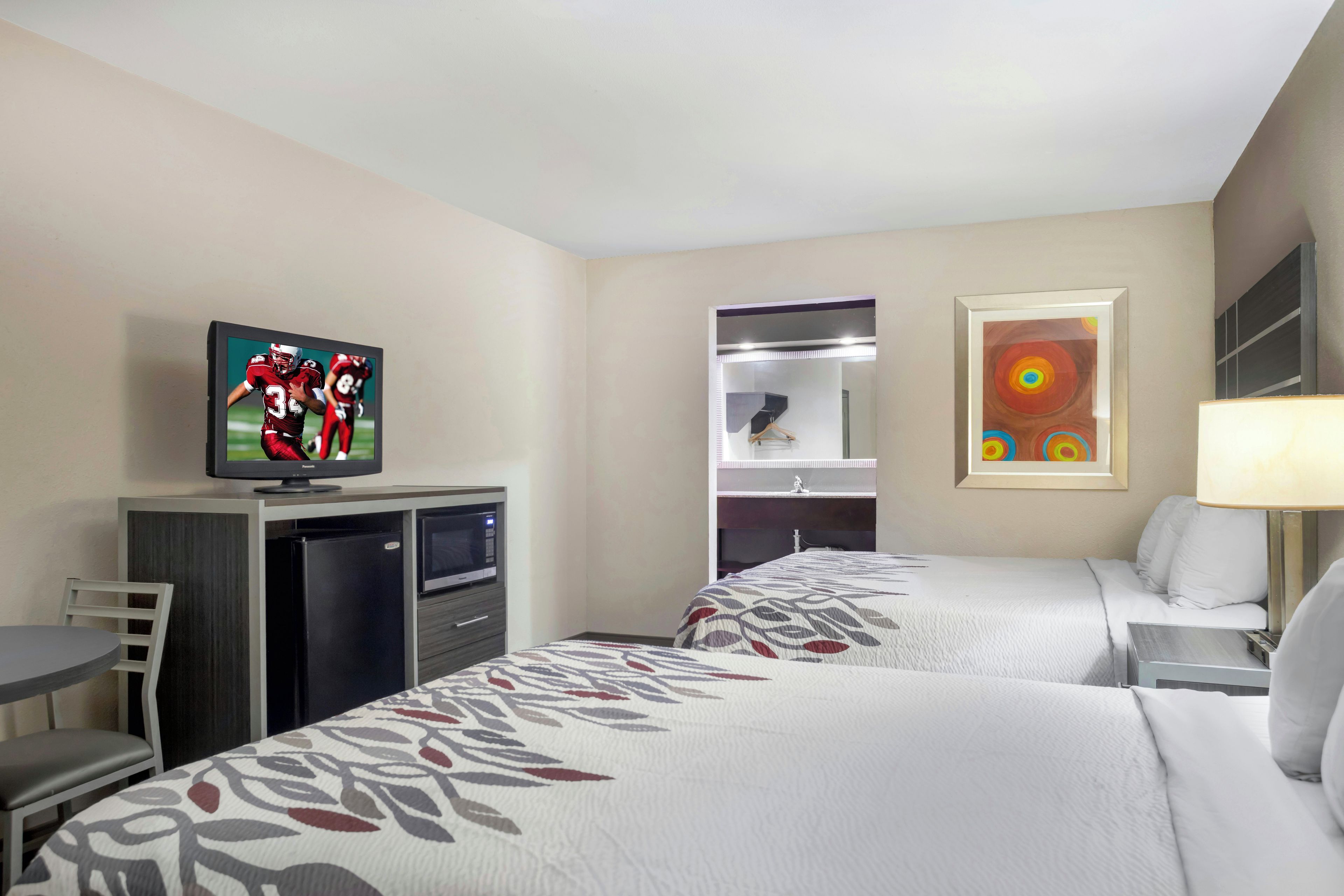 A hotel room with two beds, a television, a desk, and a wardrobe.