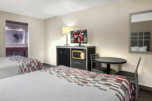 Een hotelkamer met twee bedden, een bureau met televisie, een klein tafeltje en een stoel.