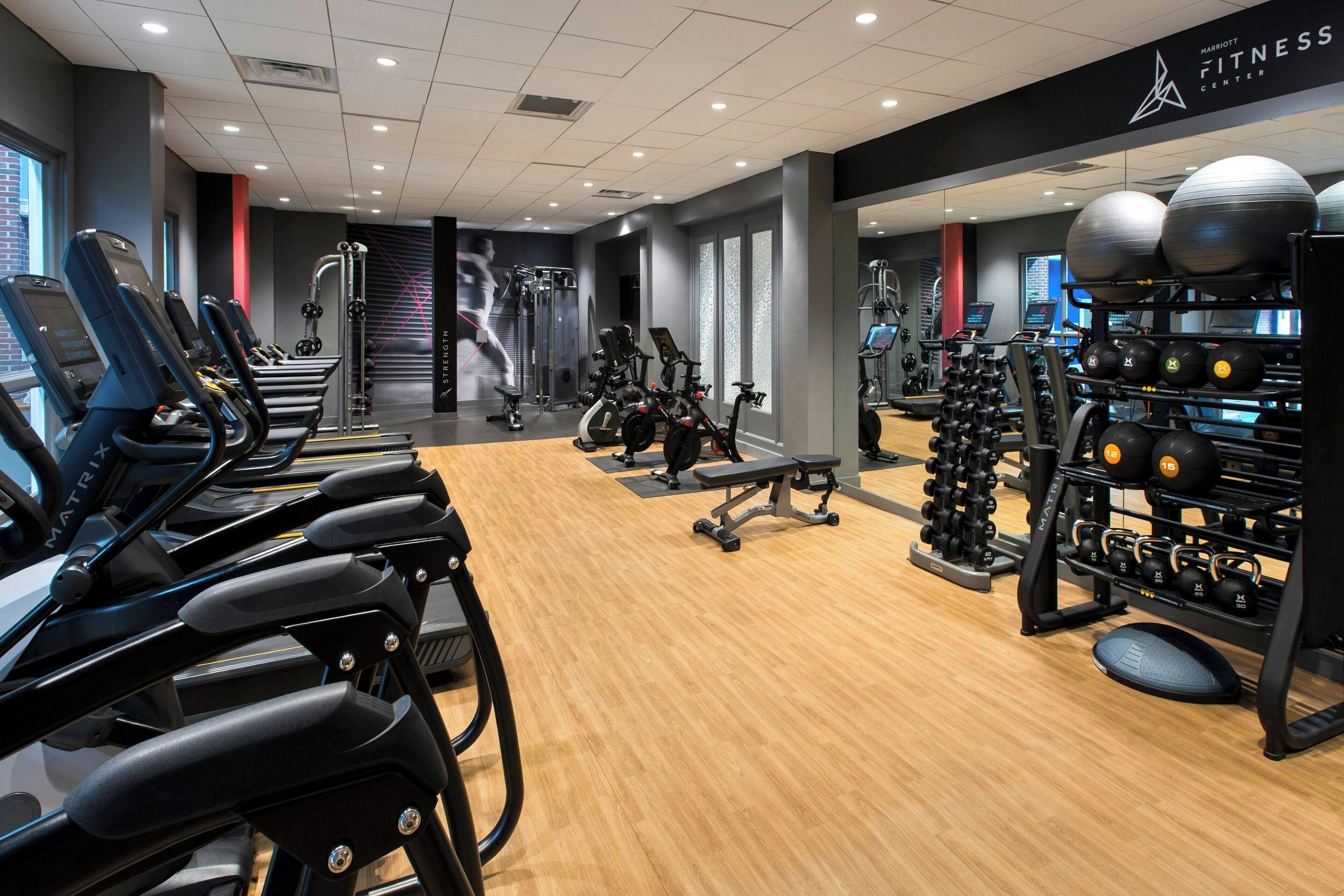 Un gimnasio moderno con cintas de correr, máquinas de pesas y pelotas de ejercicio.