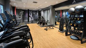 Un gimnasio moderno con cintas de correr, máquinas de pesas y pelotas de ejercicio.